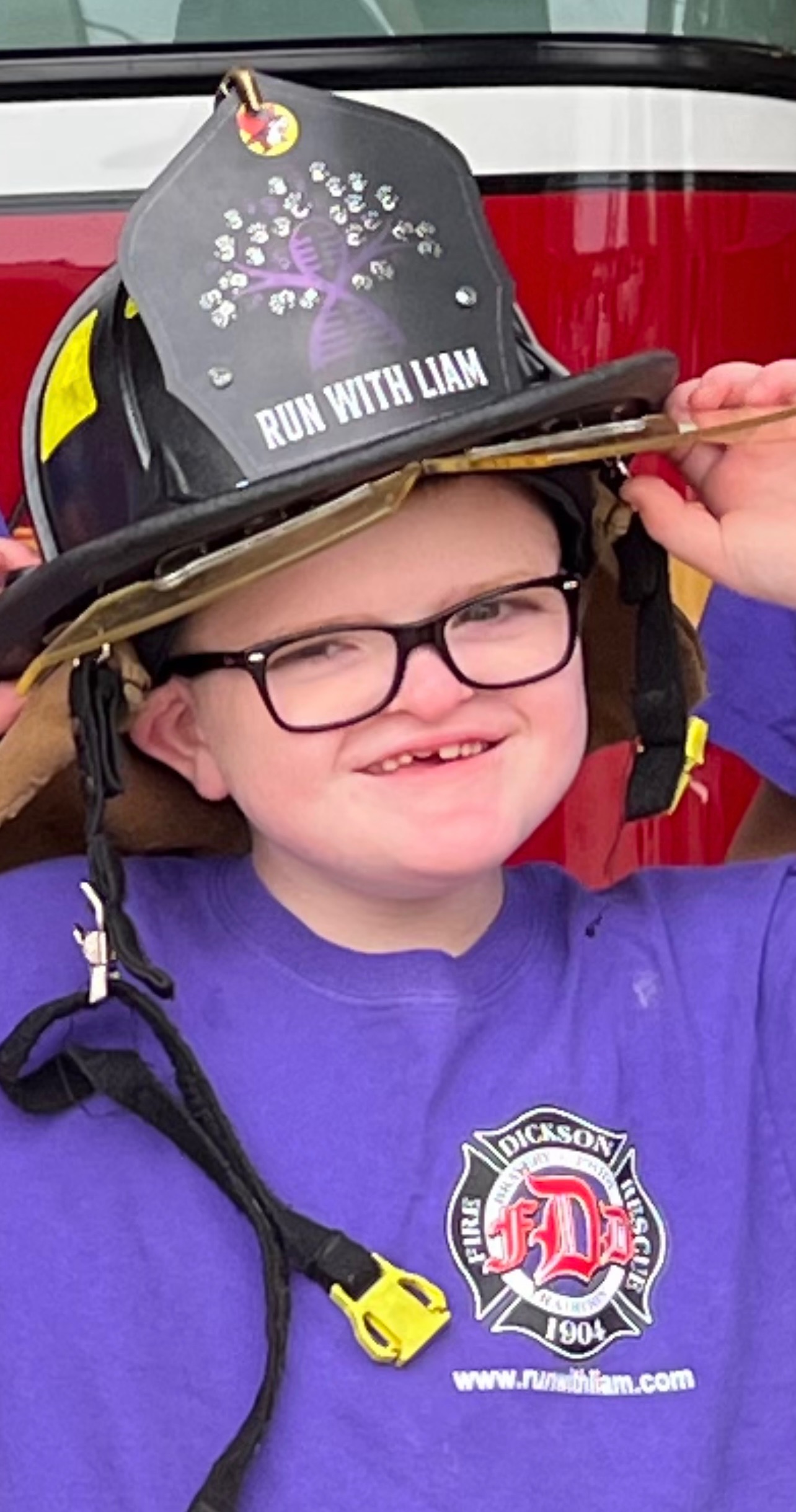 Liam wearing a Run With Liam fire helmet, smiling